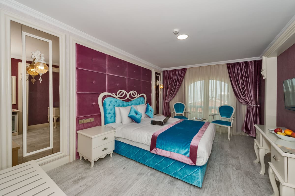 A bedroom with a large bed, a vanity with a mirror, a chair, and a desk.