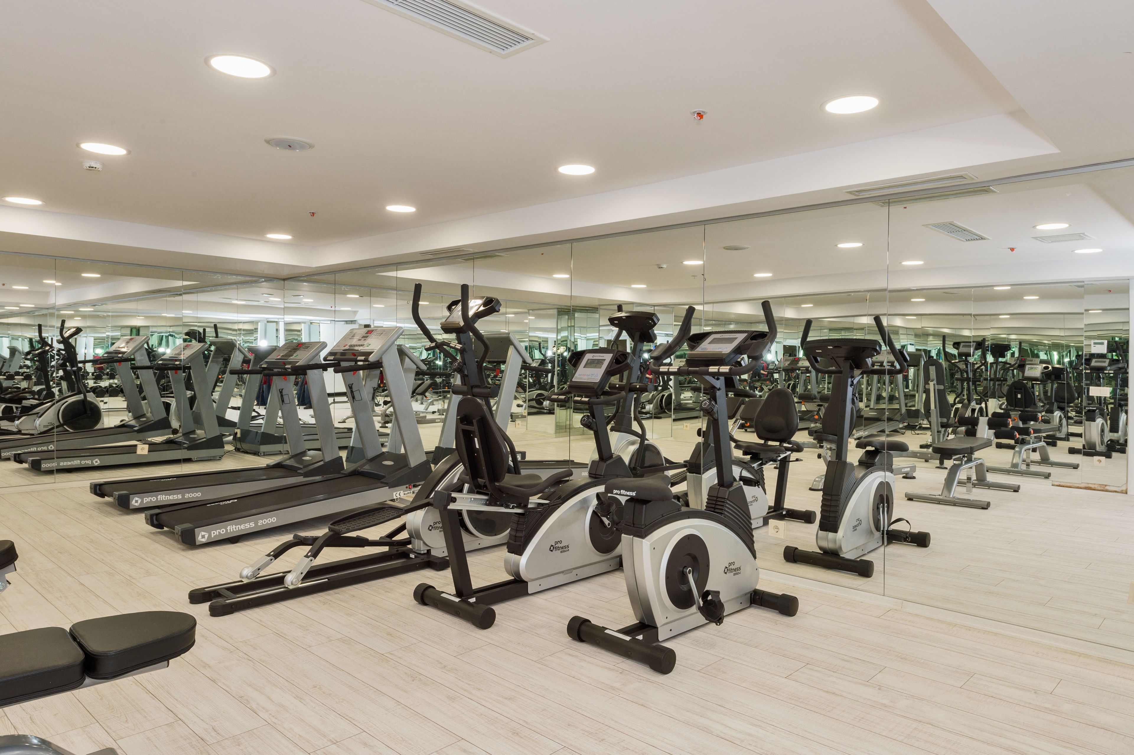 Un gimnasio con cintas de correr, elípticas y pesas libres.