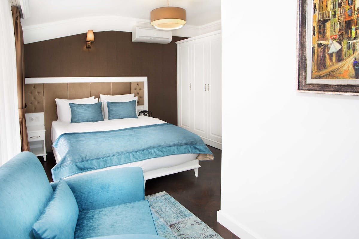 A bedroom with a bed, bedside tables, a wardrobe, a chair, and a painting on the wall.