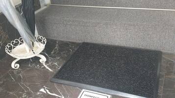 Un sol en marbre, un tapis noir et un panneau indiquant un point de désinfection.