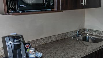 A compact kitchen with a microwave, coffee maker, and a sink.