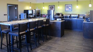 A modern kitchen with a central island, bar stools, and a microwave. - Best Western Plus Moosomin Hotel (Moosomin)