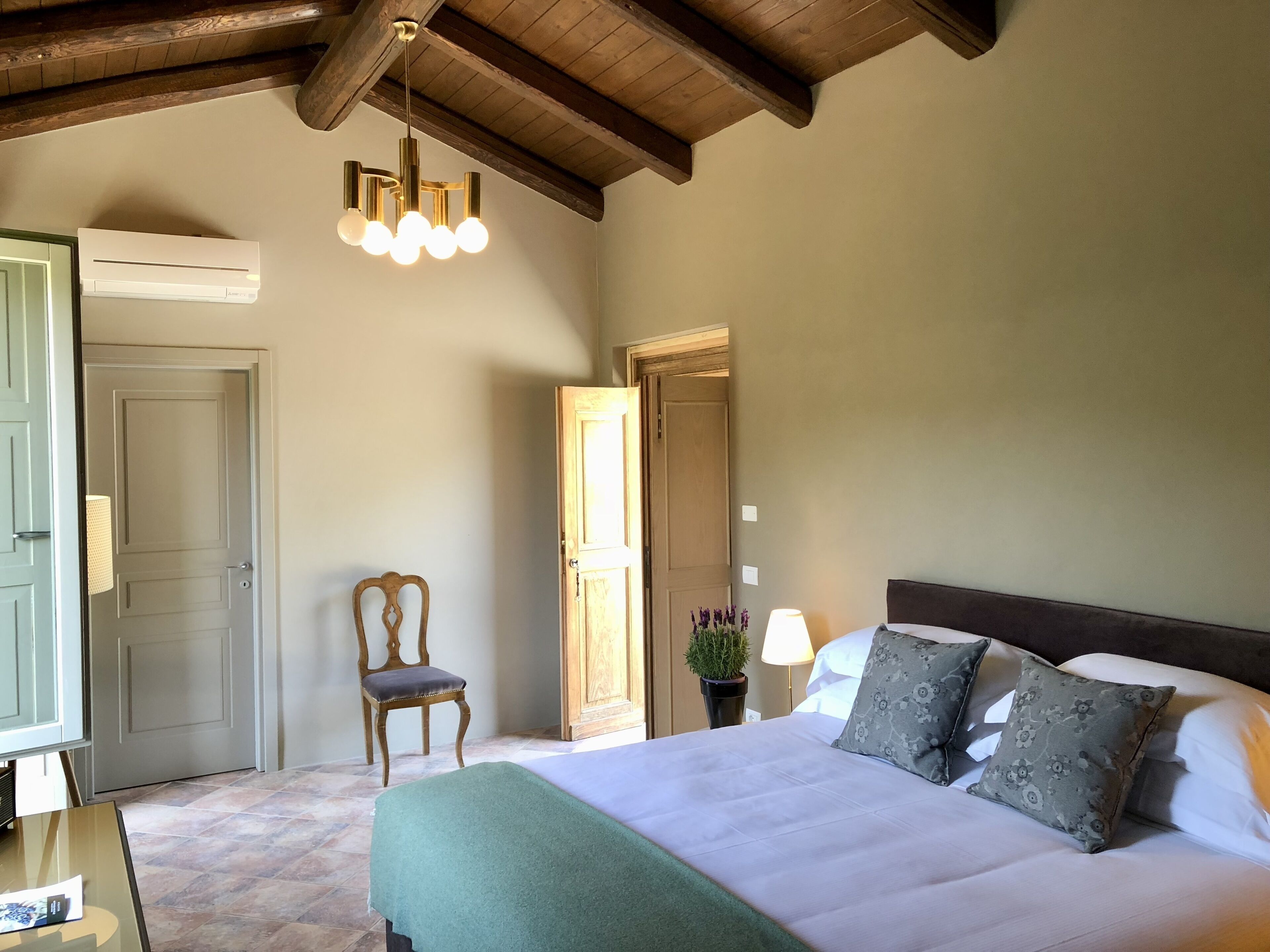Un dormitorio con cama, una silla, una mesita de noche, una lámpara y un aplique de techo.