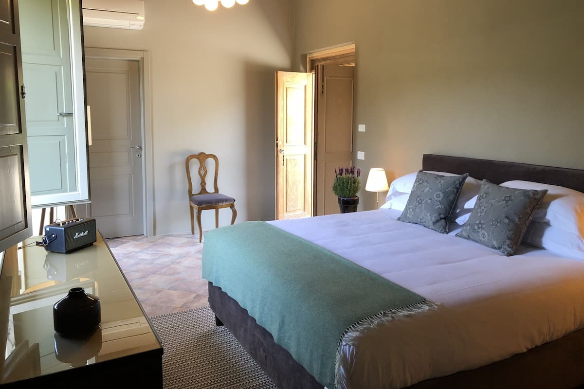 A bedroom with a bed, bedside lamp, and a chair.