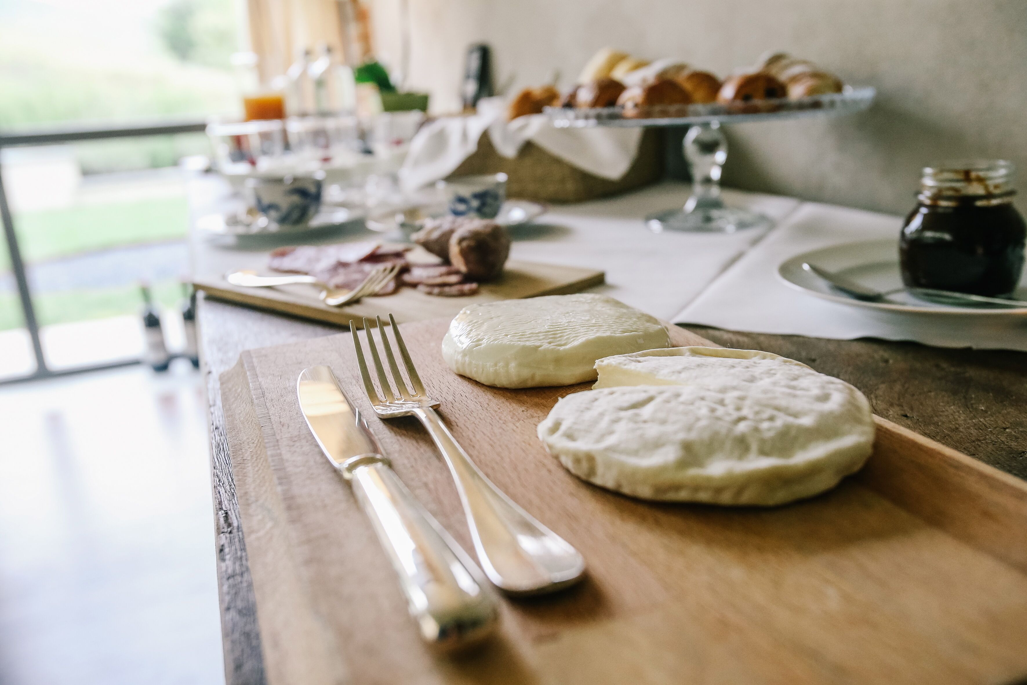 Una mesa de madera con queso, galletas y un tarro de mermelada.