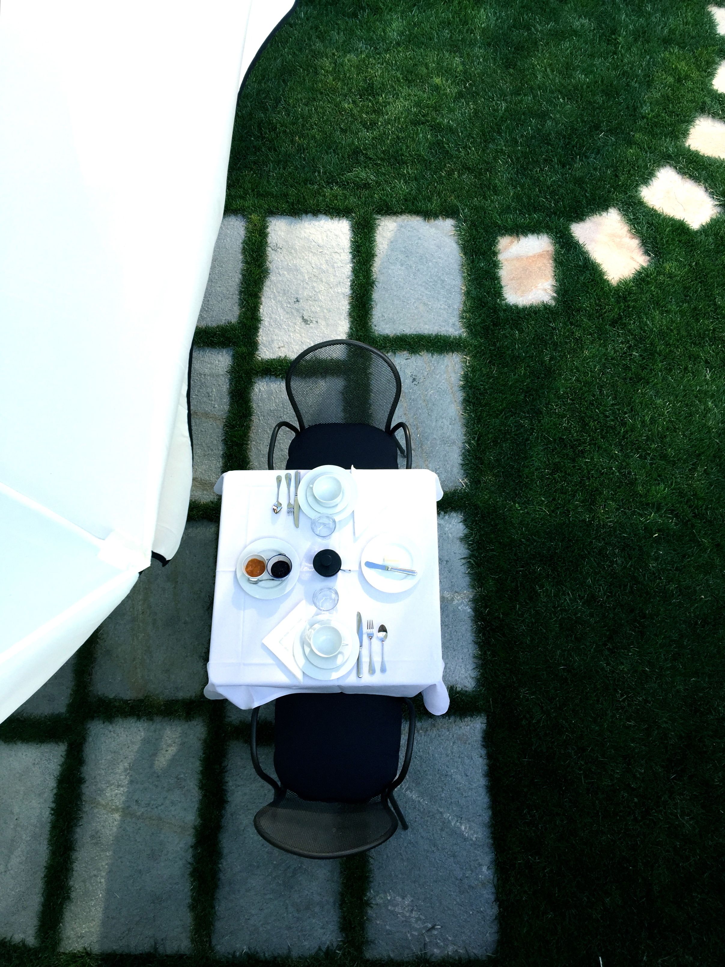 Mesa y silla al aire libre, rodeadas de un suelo estampado y césped.