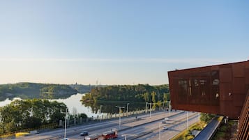 A highway with multiple lanes and vehicles, including cars and a truck, alongside a body of water and a large building with a modern design.