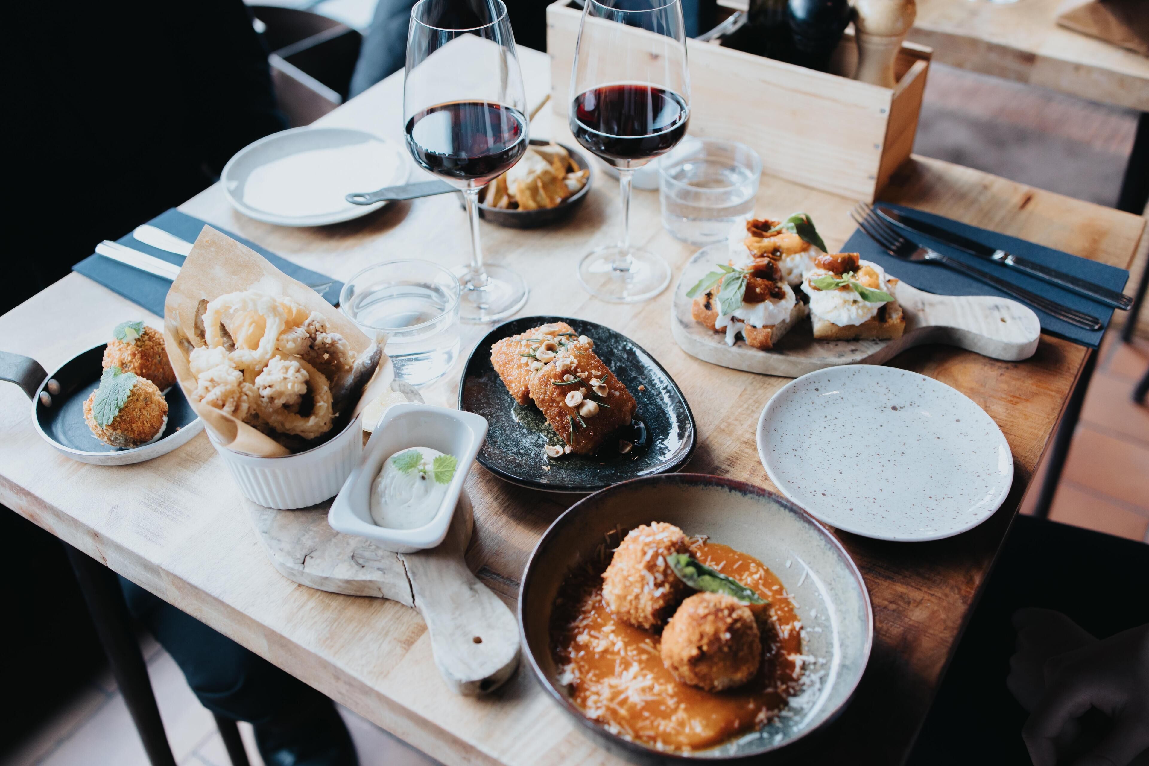 Una mesa de comedor con diferentes platos, copas de vino y cubiertos.