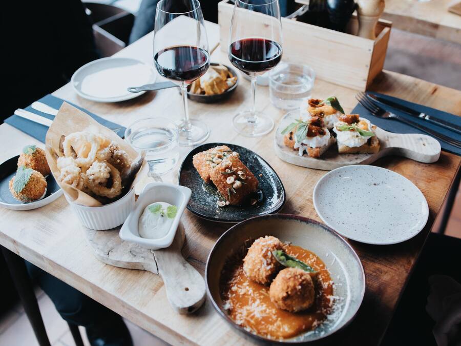 Una mesa de comedor con diferentes platos, copas de vino y cubiertos.