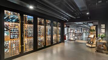 A wine cellar with glass-fronted racks filled with wine bottles.