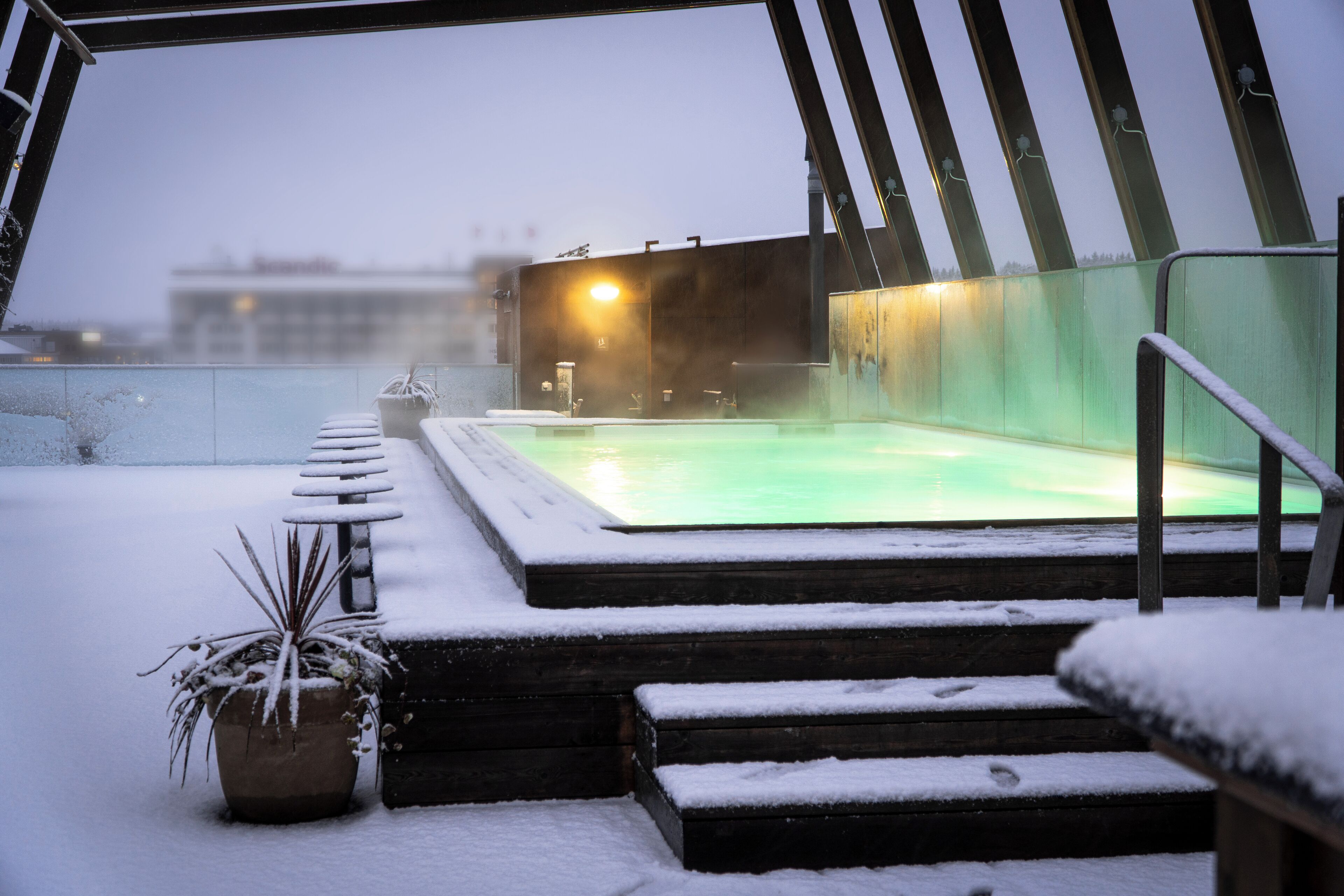 A snow-covered outdoor area with a hot tub and steps leading to it.
