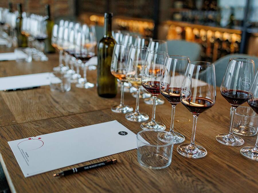 A wooden table with wine glasses and a bottle, a notepad, and a pen.