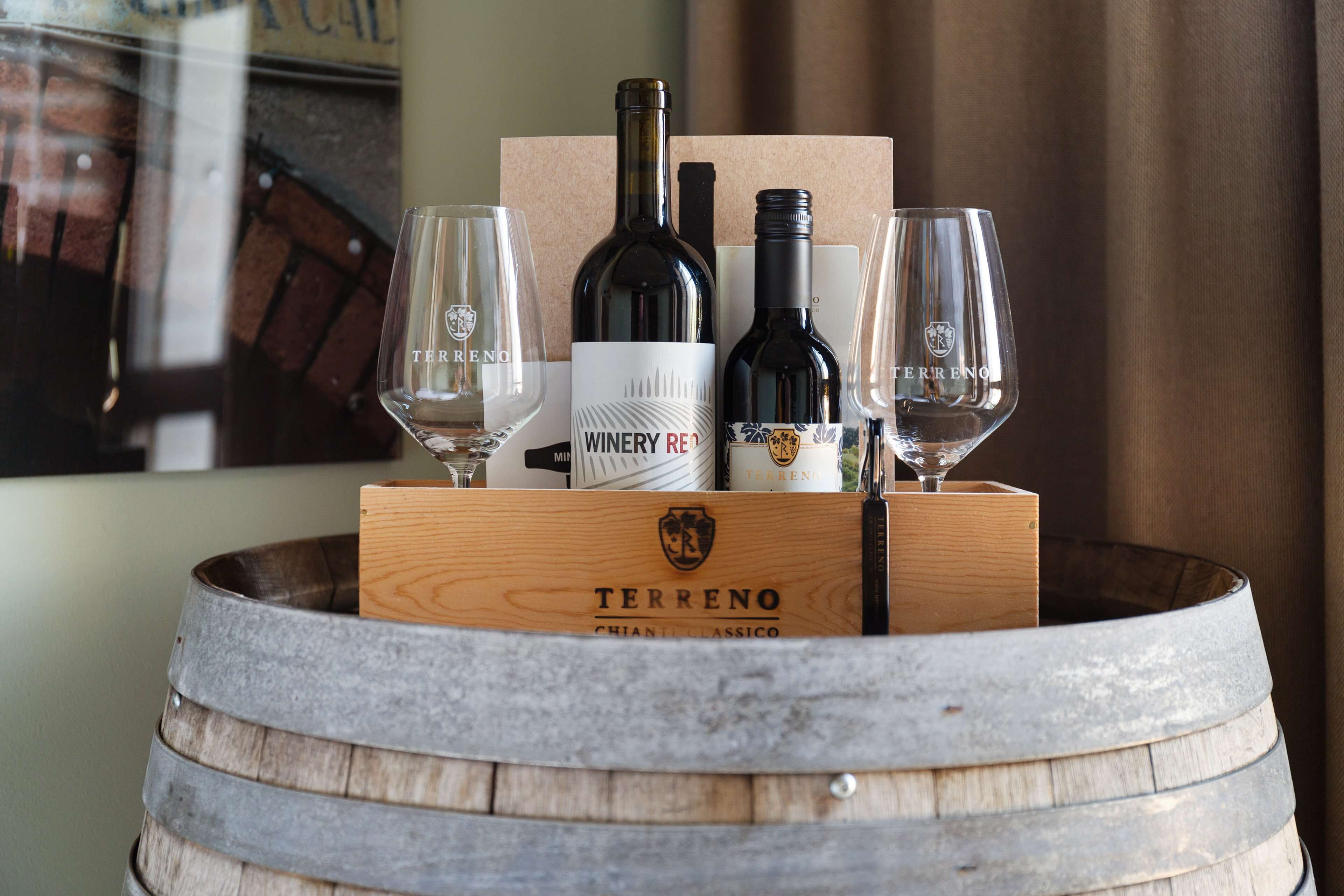 A wooden barrel containing a wine bottle, two wine glasses, and a box with the brand name "Terreno".