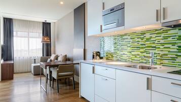 Une cuisine moderne avec des meubles blancs, un évier en acier inoxydable et un dosseret de carrelage vert.