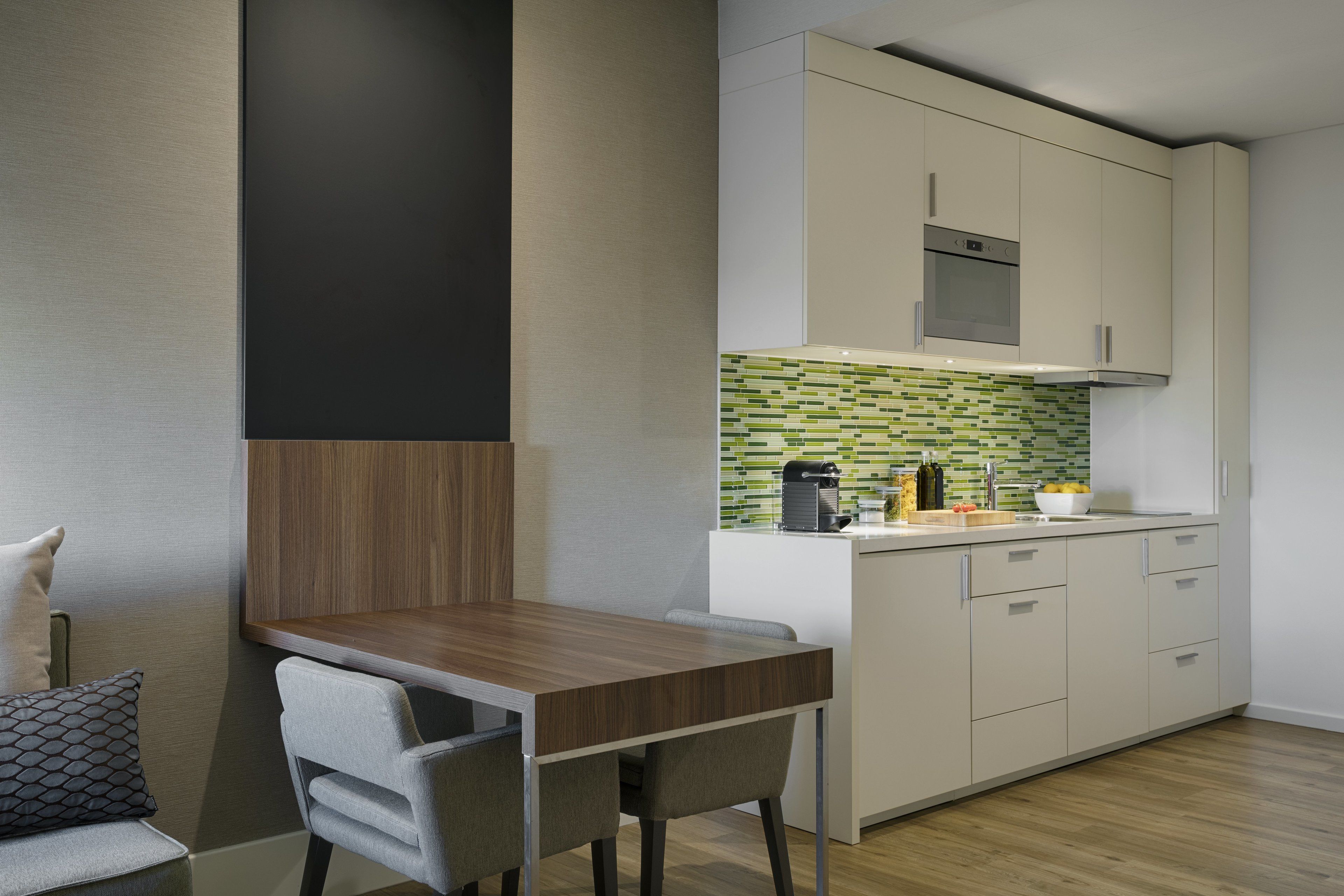 Una cocina moderna con una mesa y sillas de madera, un microondas y un salpicadero de azulejos.