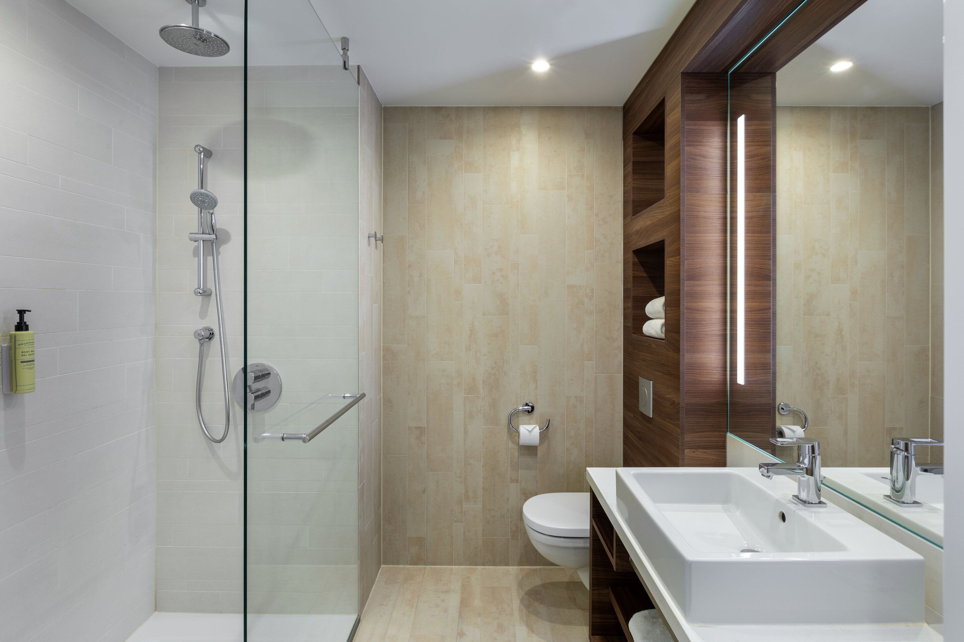 Un baño moderno con cabina de ducha de vidrio, un lavamanos blanco y un inodoro.