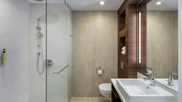 Un baño moderno con cabina de ducha de vidrio, un lavamanos blanco y un inodoro.
