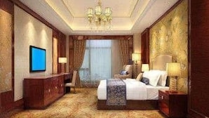 Een hotelkamer met een groot bed, een televisie, een bureau en een kroonluchter.