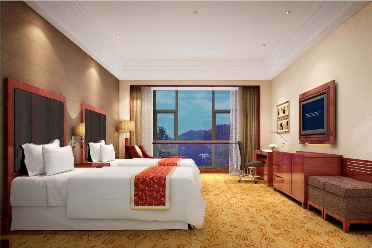 A hotel room with a large bed, a desk, a chair, and a television on the wall.