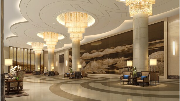 Een ruime lobby met meerdere zithoeken, grote kroonluchters en een modern design.
