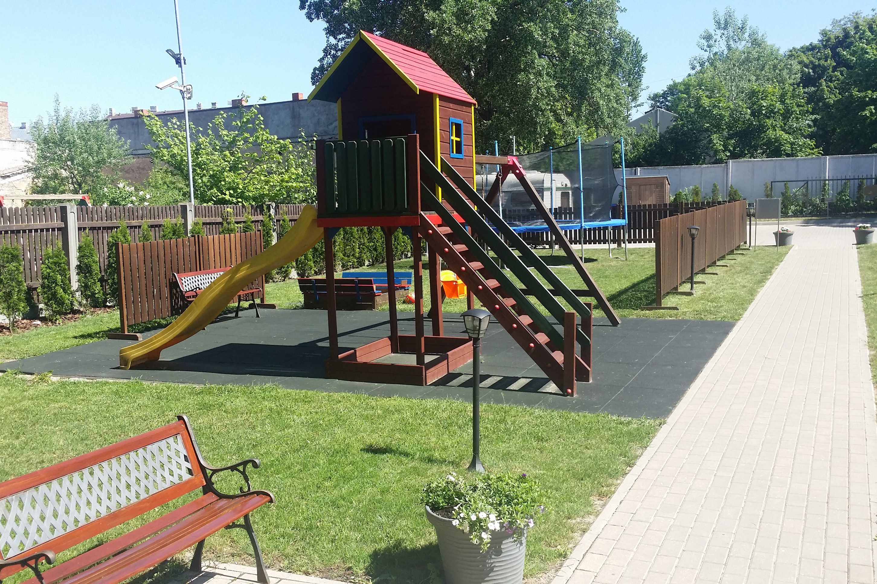 En legeplads med en rutchebane, et klatrestativ og en bænk.