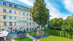 A hotel with a brick facade, a children's play area, and a well-maintained lawn. - RigaApartment SoNaDA Self Check-in Aparthotel, Center, Private Parking (Riga)