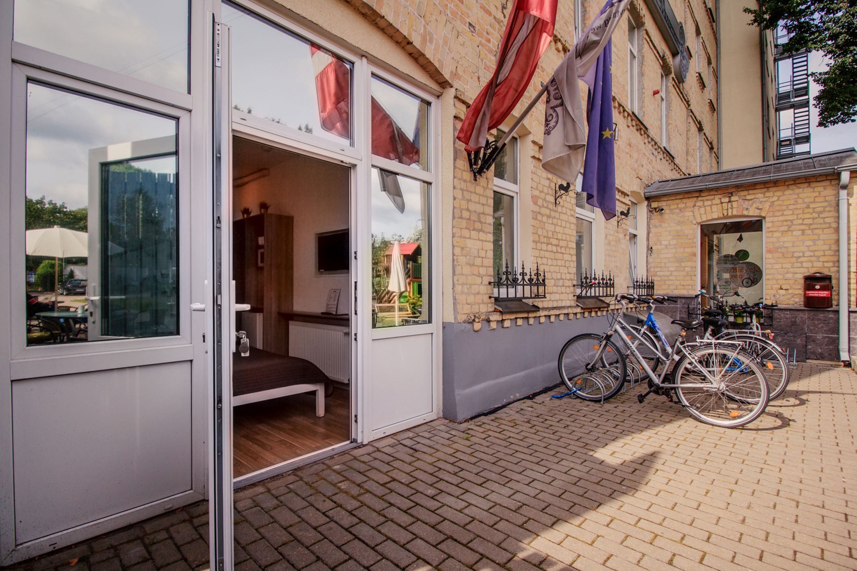 A building with a glass door entrance, a bicycle parked outside, and flags hanging on the wall.
