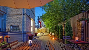 An outdoor patio with wooden benches and tables, surrounded by brick walls and greenery. - RigaApartment SoNaDA Self Check-in Aparthotel, Center, Private Parking (Riga)