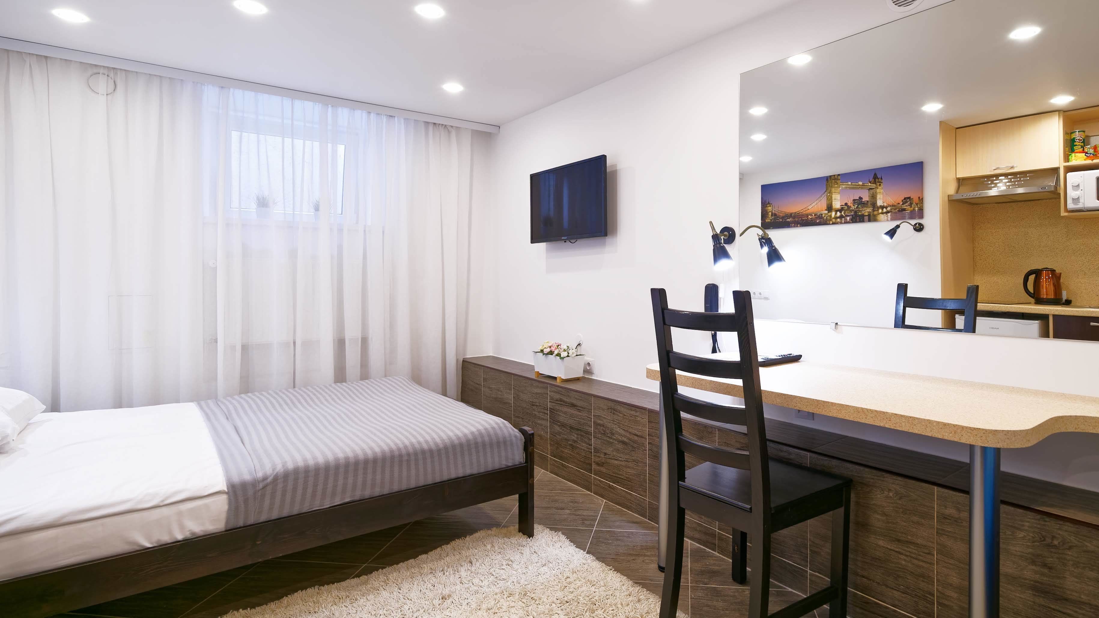 Camera d'albergo moderna con un letto, una scrivania con sedia, uno specchio grande e vista sulla città.