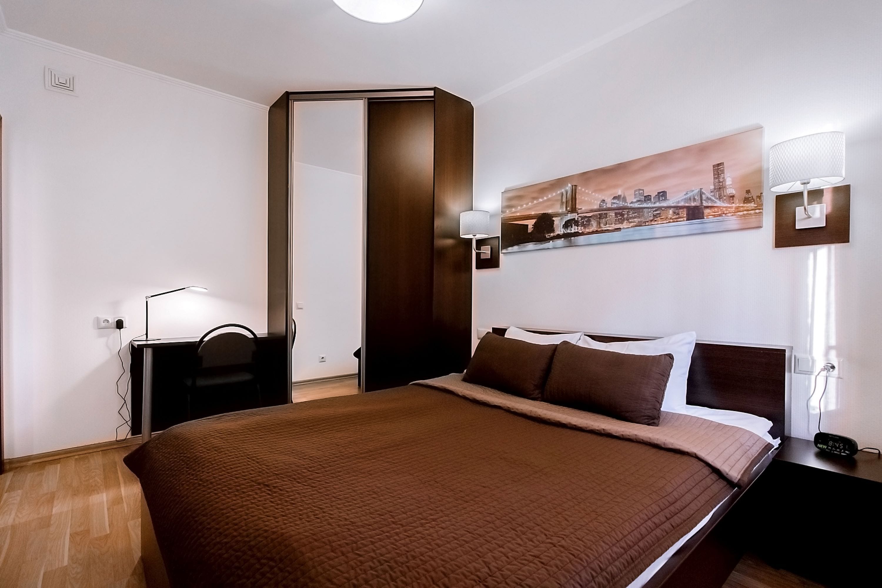Ein Hotelzimmer mit einem großen Bett, einem Schreibtisch, einem Sessel, einem Nachttisch, einer Lampe und einem Bild an der Wand.