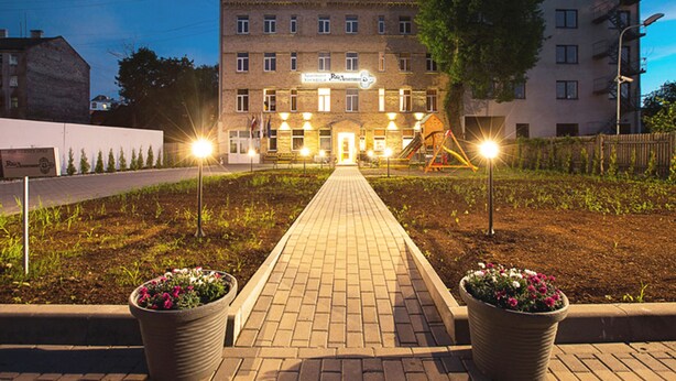 A hotel with a paved walkway leading to the entrance, surrounded by potted plants and a playground. - RigaApartment SoNaDA Self Check-in Aparthotel, Center, Private Parking (Riga)