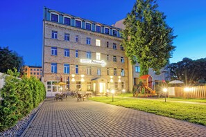 A multi-story hotel with a brick facade, outdoor seating area, and a playground.