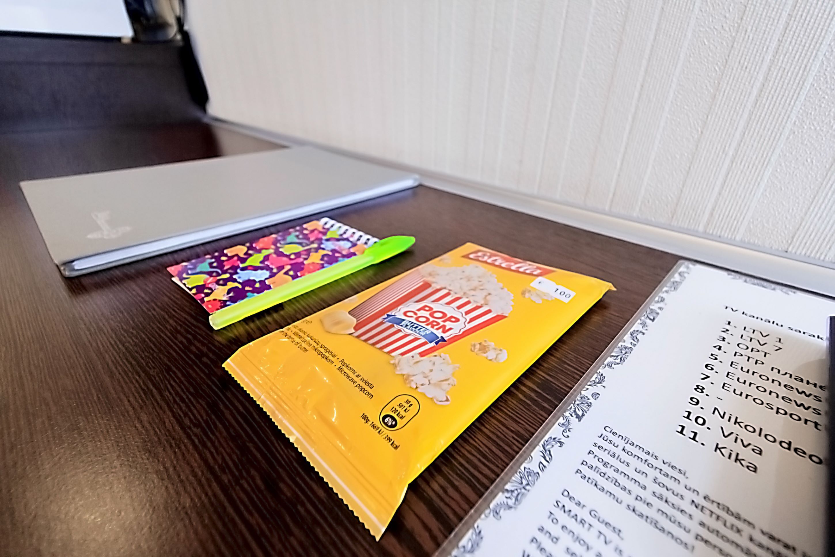 A laptop, colorful snacks, and a menu on a wooden table.