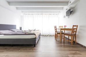 A modern hotel room with a bed, a wooden dining table, and chairs. - Ferienwohnungen Meersburg (Meersburg)