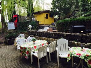An outdoor patio with white plastic chairs and tables covered with floral tablecloths. - Ferienwohnungen Meersburg (Meersburg)