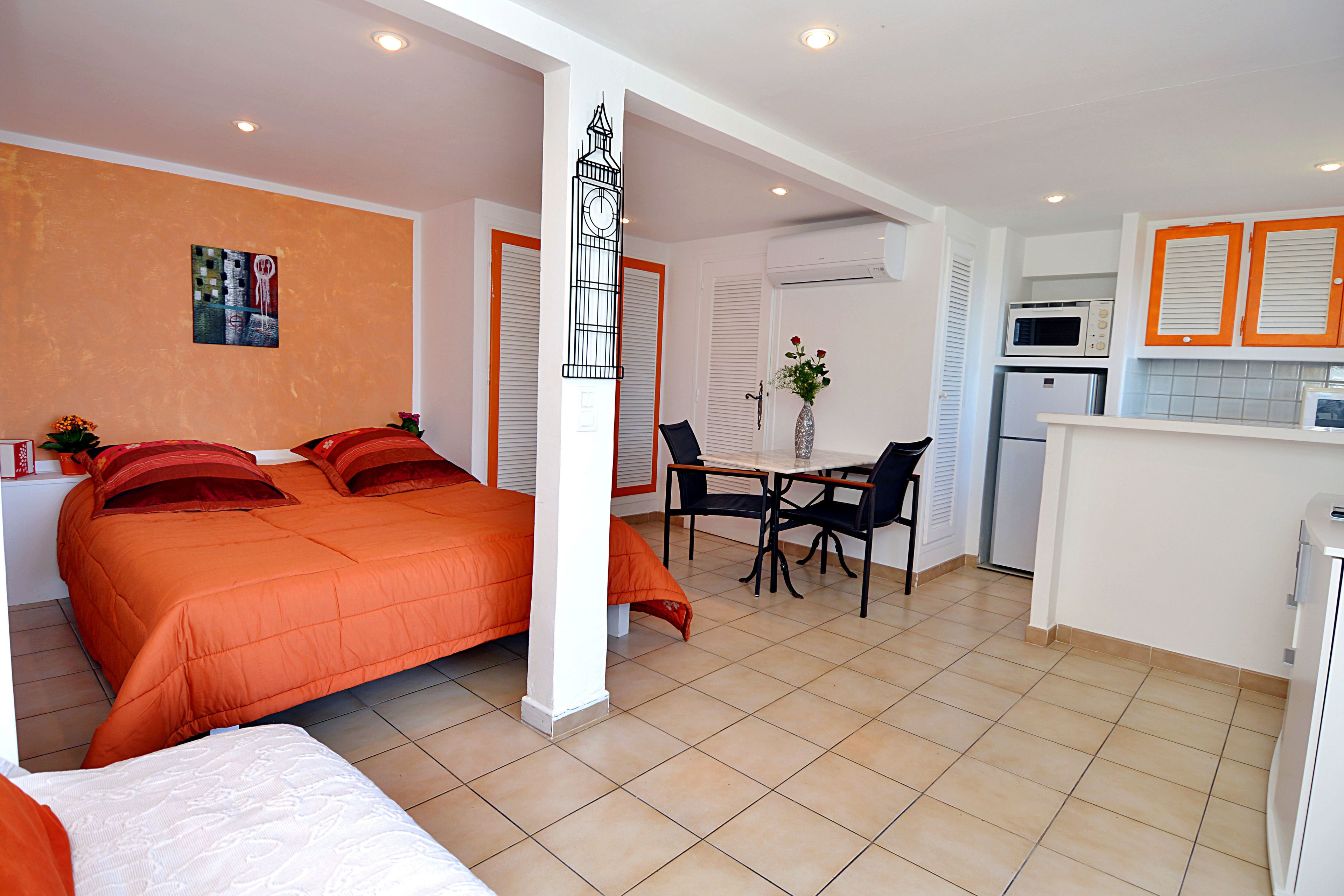 Een kleine hotelkamer met een bed, een eettafel en een kitchenette.