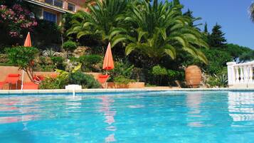 Alberca al aire libre, sombrillas en la alberca y camastros