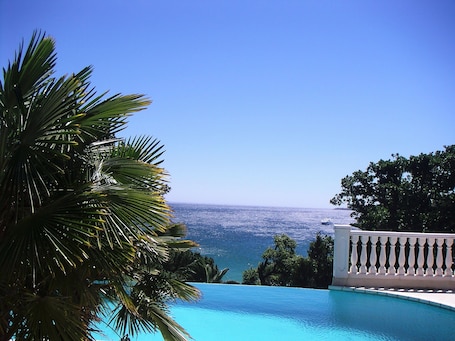 Una piscina al aire libre, sombrillas, sillones reclinables de piscina. Lou Trelus