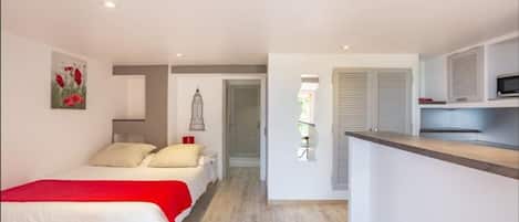 Habitació d'hotel reduïda amb llit, petita cuineta i bany.