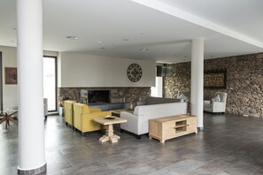 A spacious living area with a stone wall, modern furniture, and a fireplace.