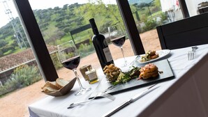 A table set for a meal with a bottle of wine, glasses, and a plate of food. - Hotel Las Monteras (Villanueva del Rey)