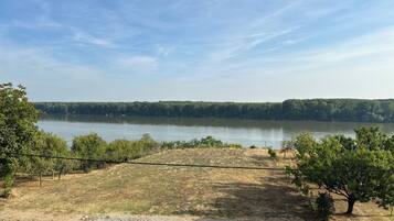 A view of a lake with a paved walkway and trees in the foreground.