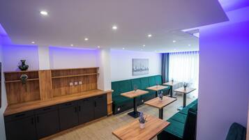 A modern interior with wooden furniture, green seating, and a cityscape painting on the wall.