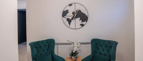 Una sala de estar moderna con dos sillones color turquesa, una mesa redonda y una obra de arte con un mapa del mundo en la pared.