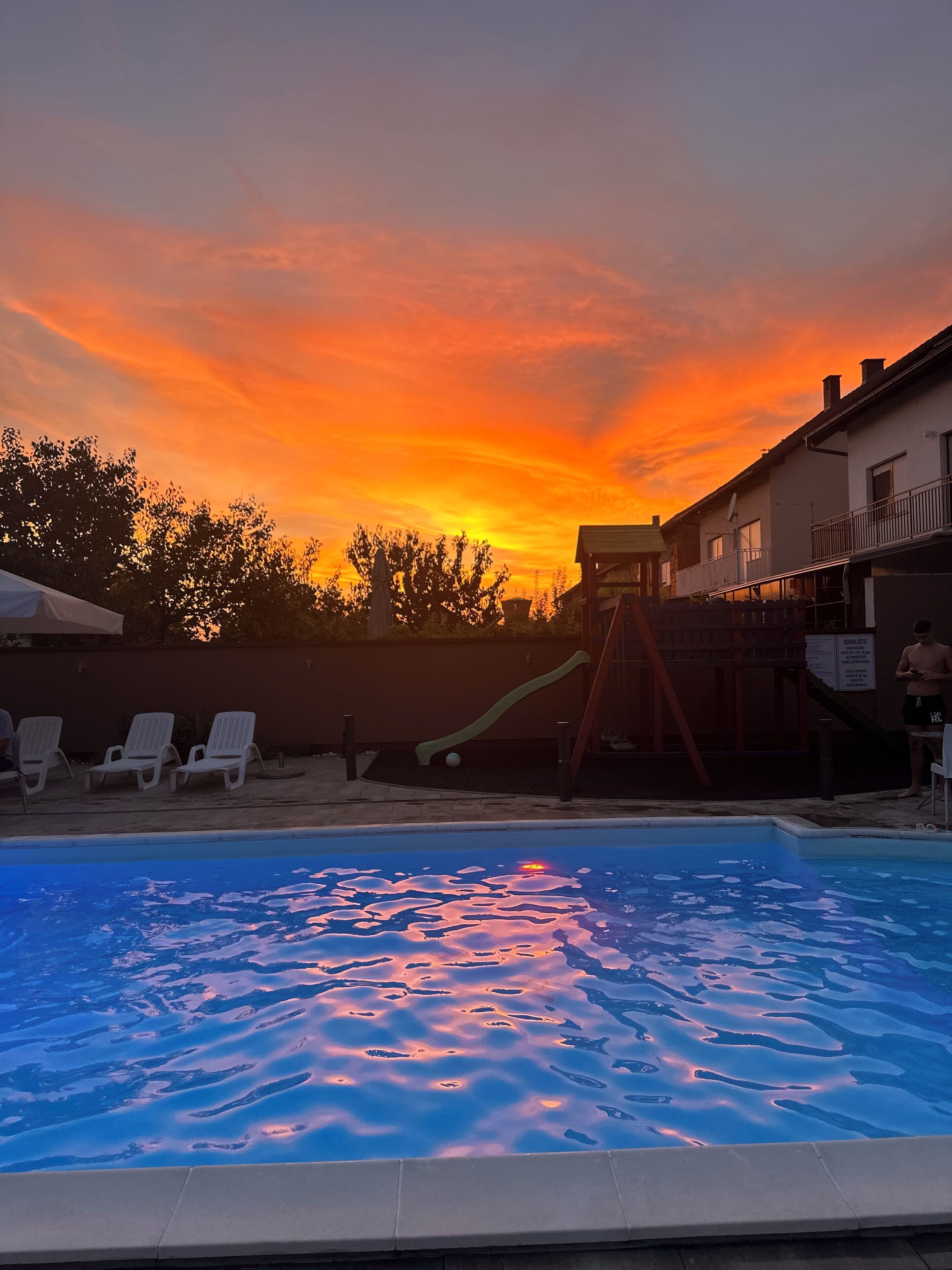 Une piscine avec un toboggan, des chaises longues et un bâtiment doté d’un balcon.
