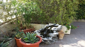 Un jardin agrémenté de plantes en pot, d’une petite cascade et d’un mur de pierres.