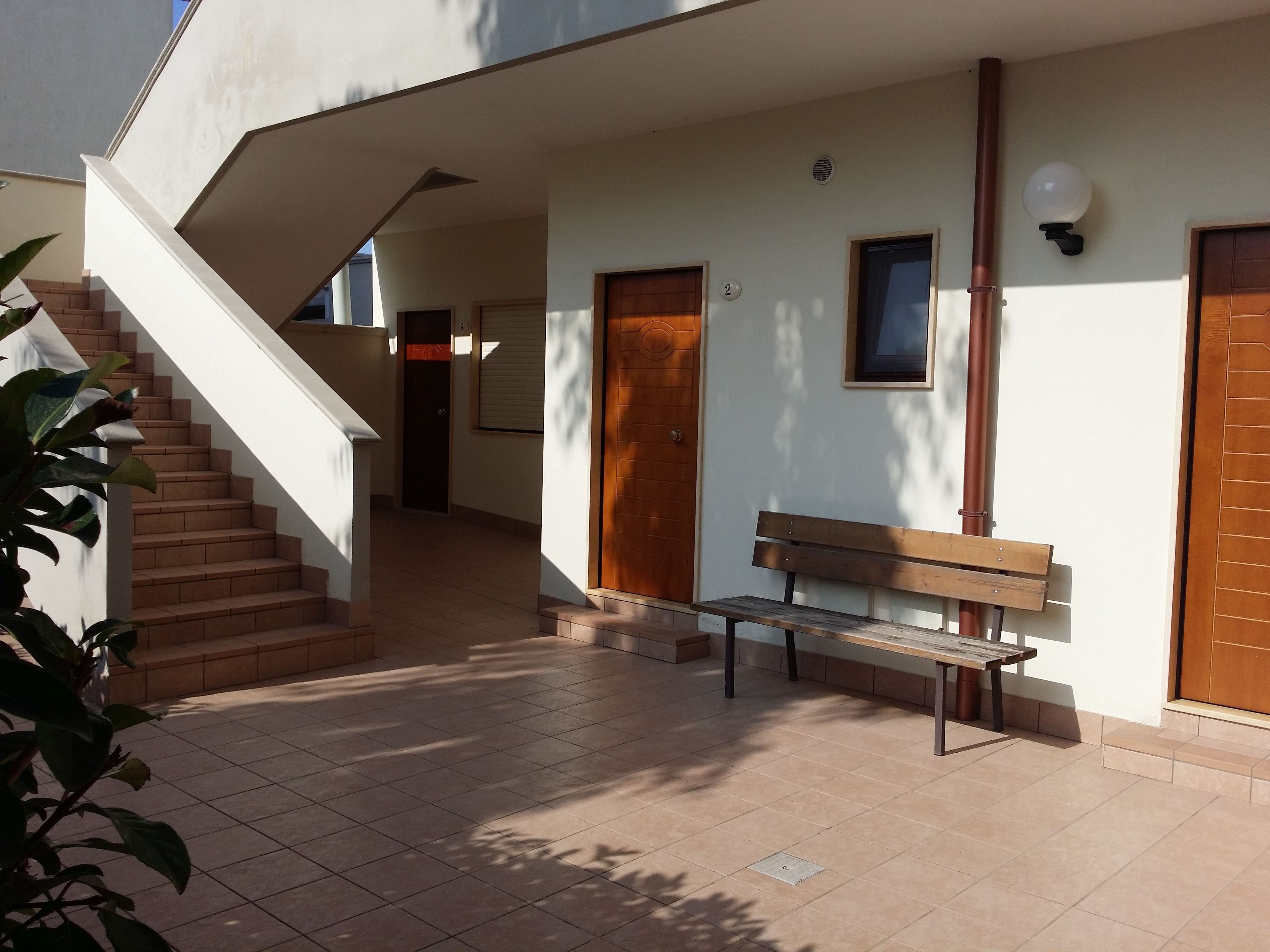 Un edificio moderno con una scala, una panchina e una porta.