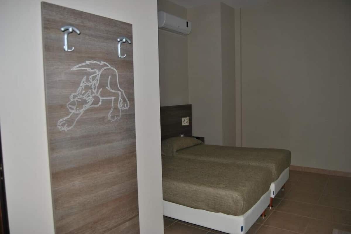 Een slaapkamer met een bed, een houten paneel met een illustratie van een hond en een wandairconditioner.