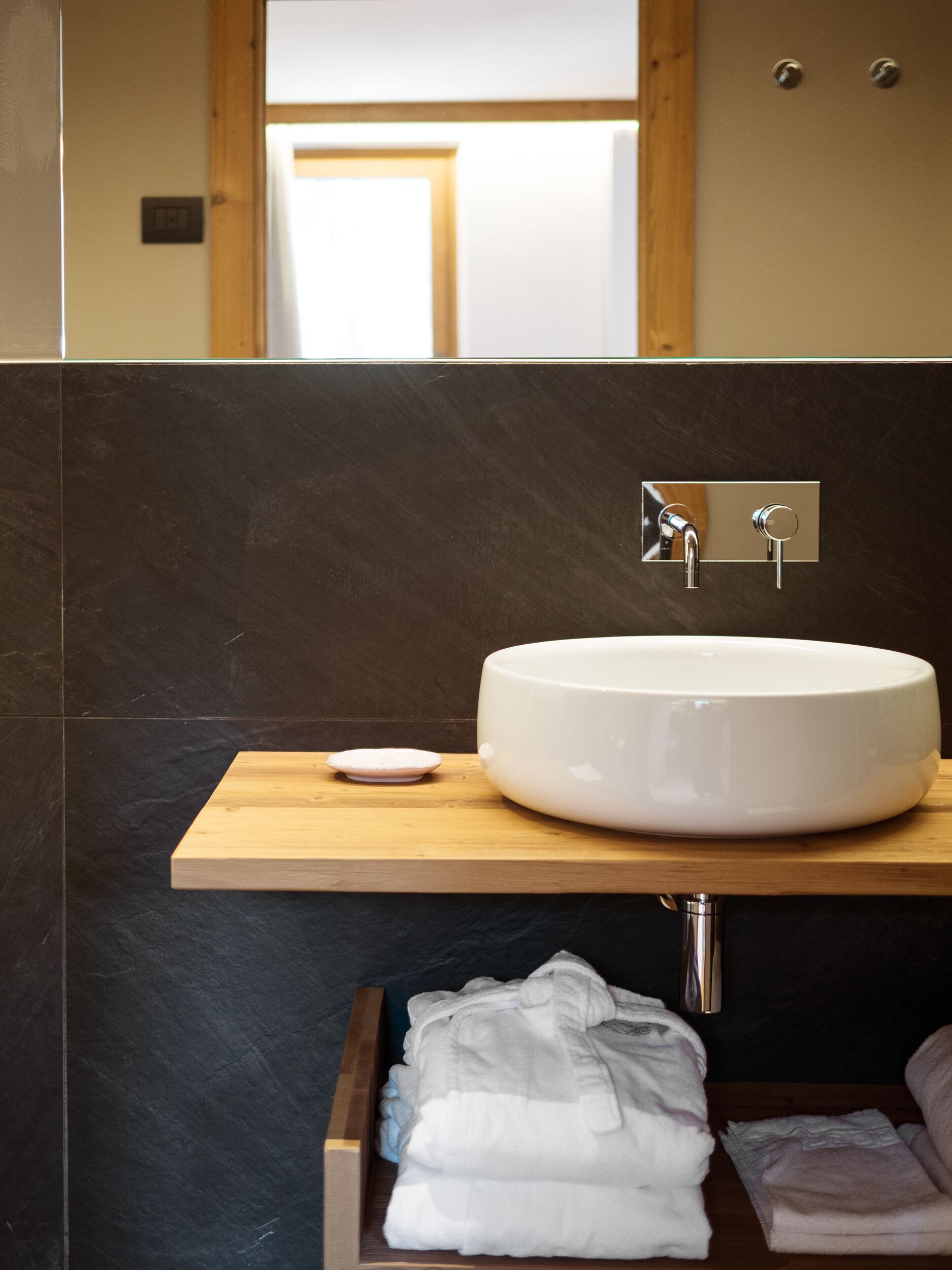 A modern bathroom with a large white sink, a wooden countertop, and a mirror above the sink.