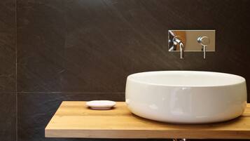 A modern bathroom with a large white sink, a wooden countertop, and a mirror above the sink.
